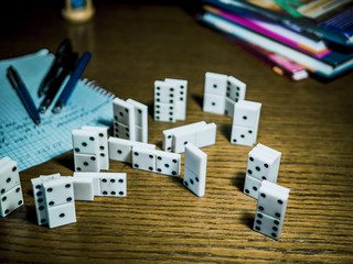 domino pieces with books and pens on the table