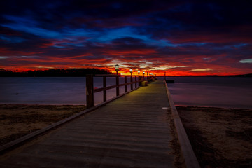 Long jetty with light at a colorful sunset