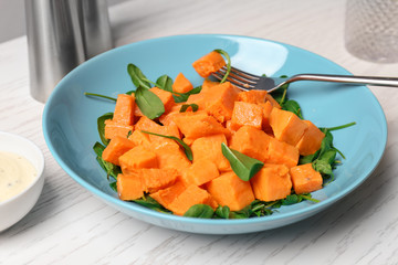Plate with delicious cut sweet potato on table