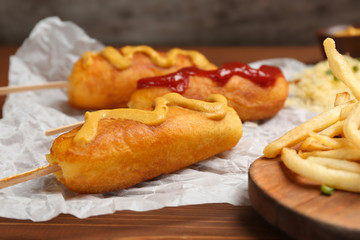 Naklejka na ściany i meble Tasty corn dogs with sauces on table, closeup