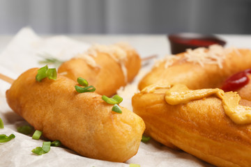 Tasty corn dogs with mustard on table, closeup