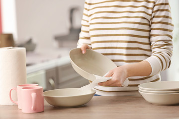 Woman wiping dishware with paper towel in kitchen