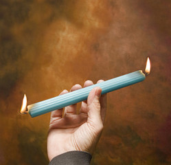 man holding burning candle lit lighted at both ends