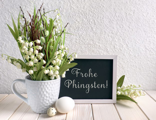 Blackboard decorated with lily of the valley flowers and eggs, text
