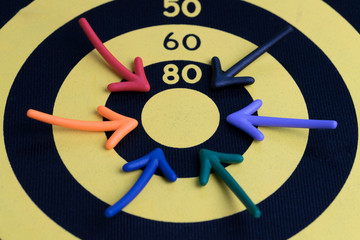 Business success target concept, multi colorful magnet arrows pointing at center score of yellow with black circle dartboard