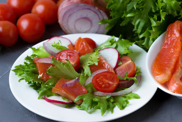 Fresh salad from salmon and vegetables on a white plate.