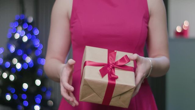Closeup of a woman's hands holding and fumbling a Christmas gift or present. A happy wife concept. Soft focus