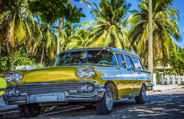 Goldener amerikanischer Oldtimer parkt unter blauem Himmel und Palmen in Varadero Kuba - Serie Cuba...