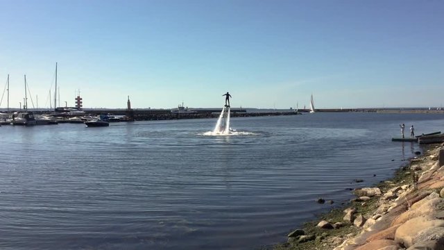 Man standing over the water on flyboard in the yacht harbor