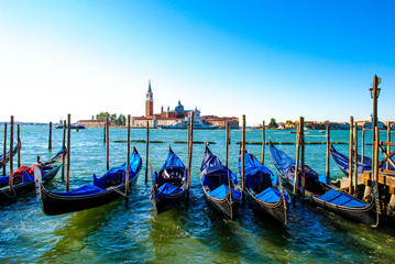 Fototapeta na wymiar Venetian Gondolas Parked in the Canal in Venice, Italy