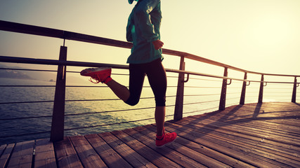 sporty fitness female runner running on seaside boardwalk during sunrise - obrazy, fototapety, plakaty