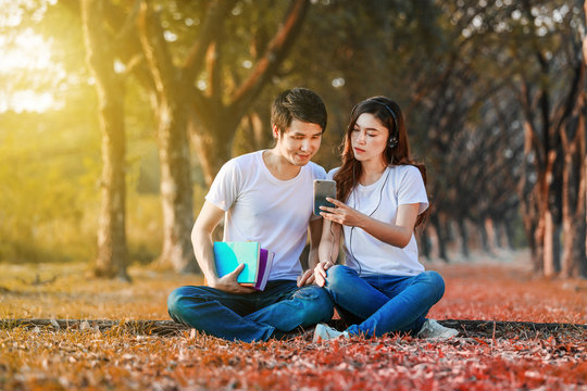 couple listening music from mobile with headphone in the park