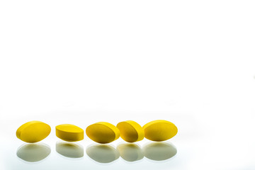 Yellow oval tablet pills with shadows on white background with beautiful creative pattern and copy space for text. Mild to moderate pain management. Pain killer medicine.
