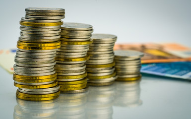 Macro shot detail of golden and silver color coin stacks on  with banknotes . Business and finance growth, saving money, investment and interest concept.