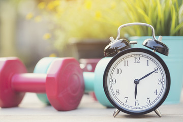Time for exercising clock and dumbbell with colorful background