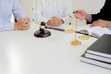 Judge gavel with Justice  lawyers having team meeting at law firm in background. Concepts of law.