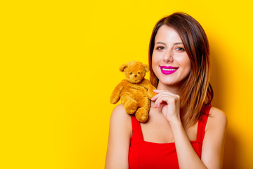 girl in red dress with teddy bear toy on shoulder