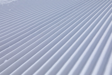 Obraz premium Diagonal track lines on a ski slope left by a snowcat