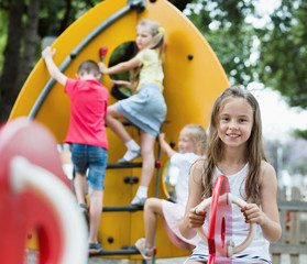 Fototapeta na wymiar Smiling girl sitting on swing on children's playground