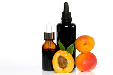 apricot oil .organic natural apricot oil in glass dark brown bottles and fresh apricot fruits on a white background 