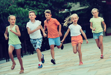 Group of cheerful children running together in town on summer