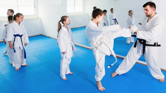 Boys kicking with coach during karate class