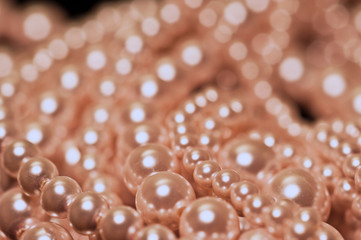 Various strands of pink pearls on a black background