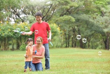 Fototapeta premium Asian family are blowing soap bubbles together.
