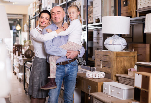 Family couple with small daughter in furniture shop