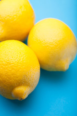 Close-up, three yellow lemons on a blue background.