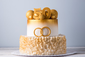 Beautiful cake for the 50th anniversary of the wedding decorated with gold balls and rings. Concept of festive desserts