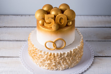 Beautiful cake for the 50th anniversary of the wedding decorated with gold balls and rings. Concept...