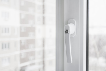 White secure UPVC window with lockable handle. Closeup, selective focus