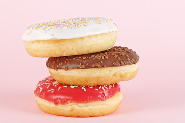 Three donuts with icing on pink background. Sweet donuts.