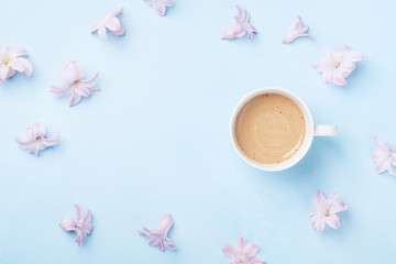 Pink flowers and coffee on blue pastel background top view. Creative and fashion composition. Flat lay style.