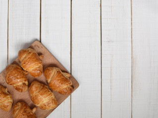 Freshly baked homemade croissants with golden crust on a white retro wooden table. top view. space for text.