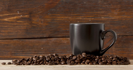 Seeds of coffee in a black cup on a wooden background