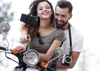 Male and female on motor scooters in a town.