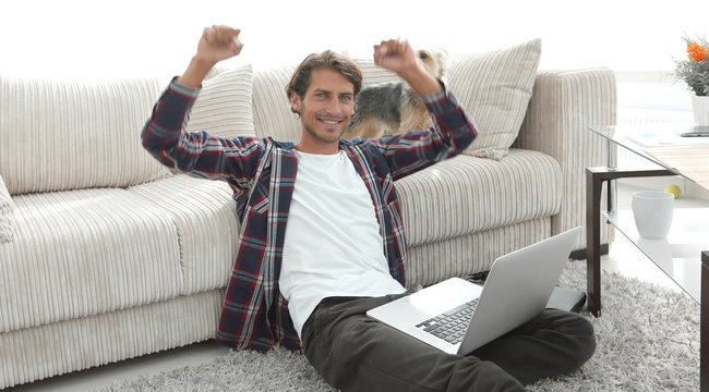 happy young man exults with his dog sitting in the living room