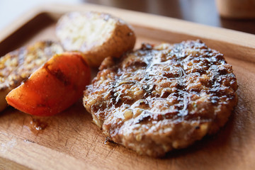 Grilled meat. Slice red tomato. Brown background