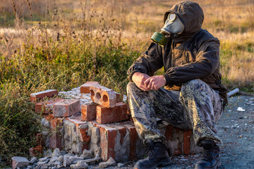 old bricks from destroyed building and man sitting in gas mask on these bricks