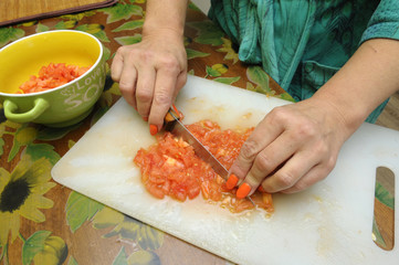 A housekeeper’s hands slicing vegetables on a chopping board