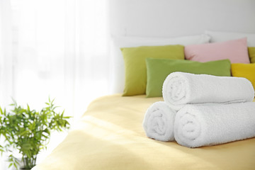 Fototapeta na wymiar Rolled white towels on bed