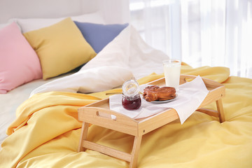 Tray with tasty breakfast on bed