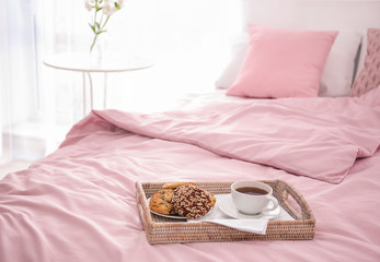 Tray with tasty breakfast on bed
