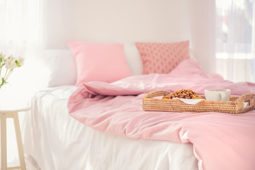 Tray with tasty breakfast on bed