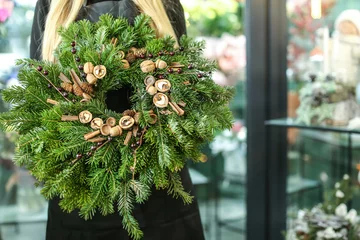 Cercles muraux Fleuriste Female florist with Christmas wreath in flower shop
