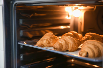 Baking tray with delicious croissants in oven