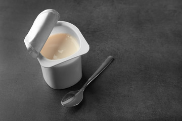 Plastic cup with yogurt on dark background