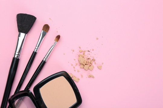 Facial powder and brushes of professional makeup artist on color background